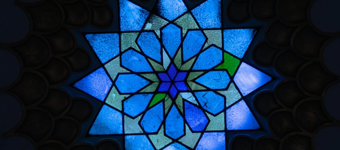 A photo of a blue, multi-pointed star, stained glass window in a Jewish temple.