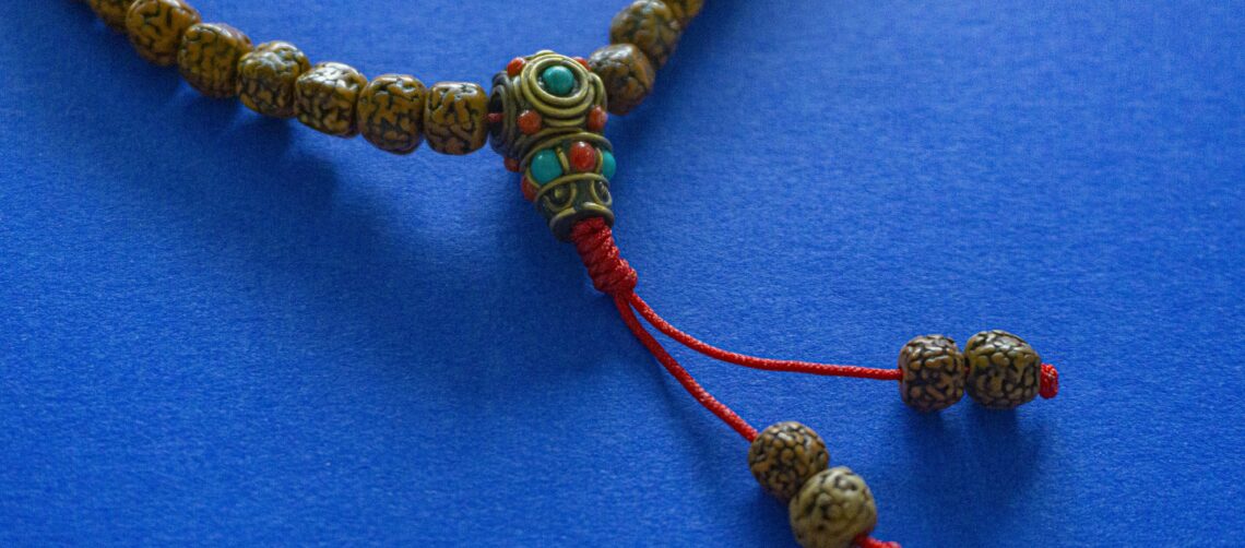 A photo of Rudraksha buddhist mala (beads) against a blue background.