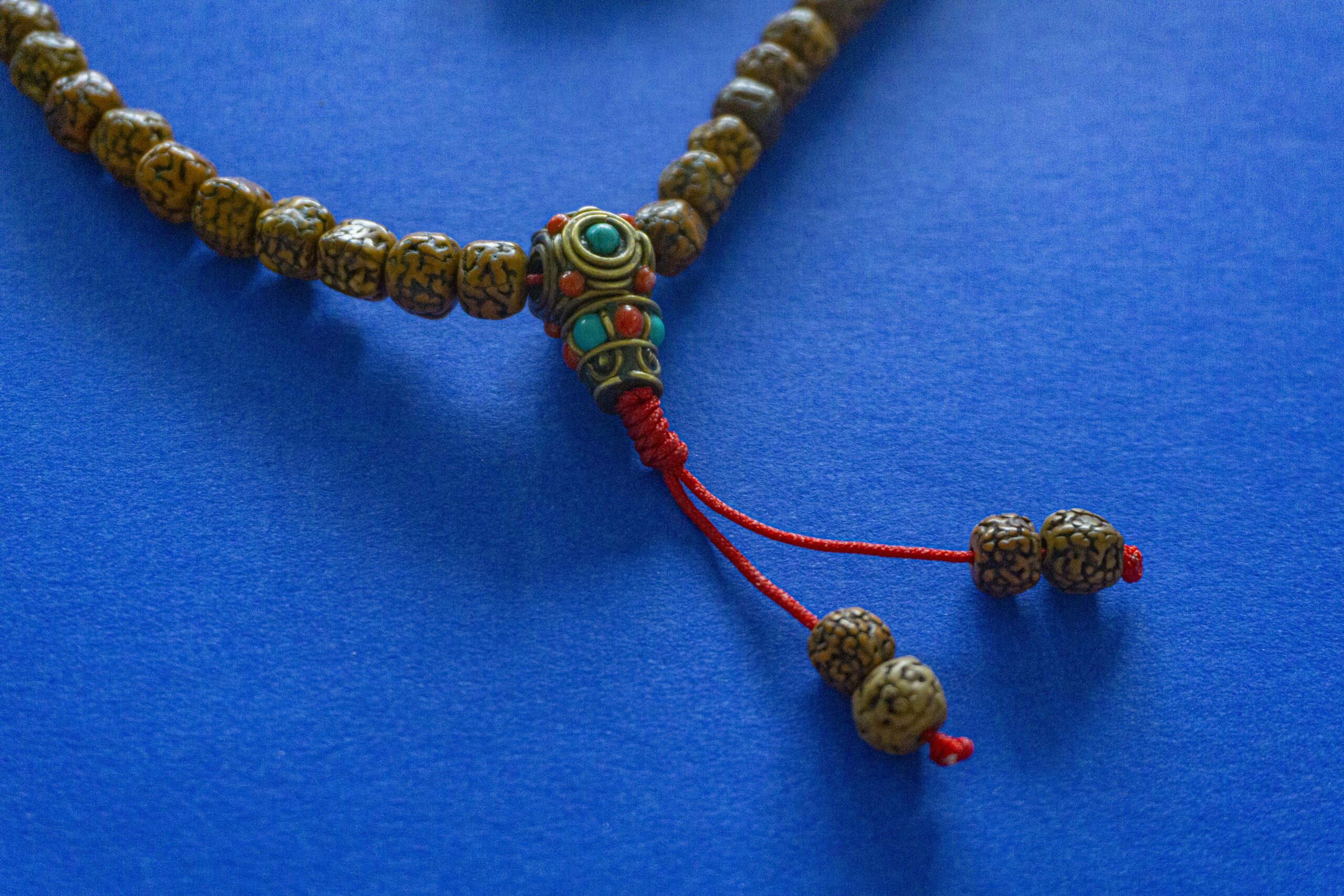 A photo of Rudraksha buddhist mala (beads) against a blue background.