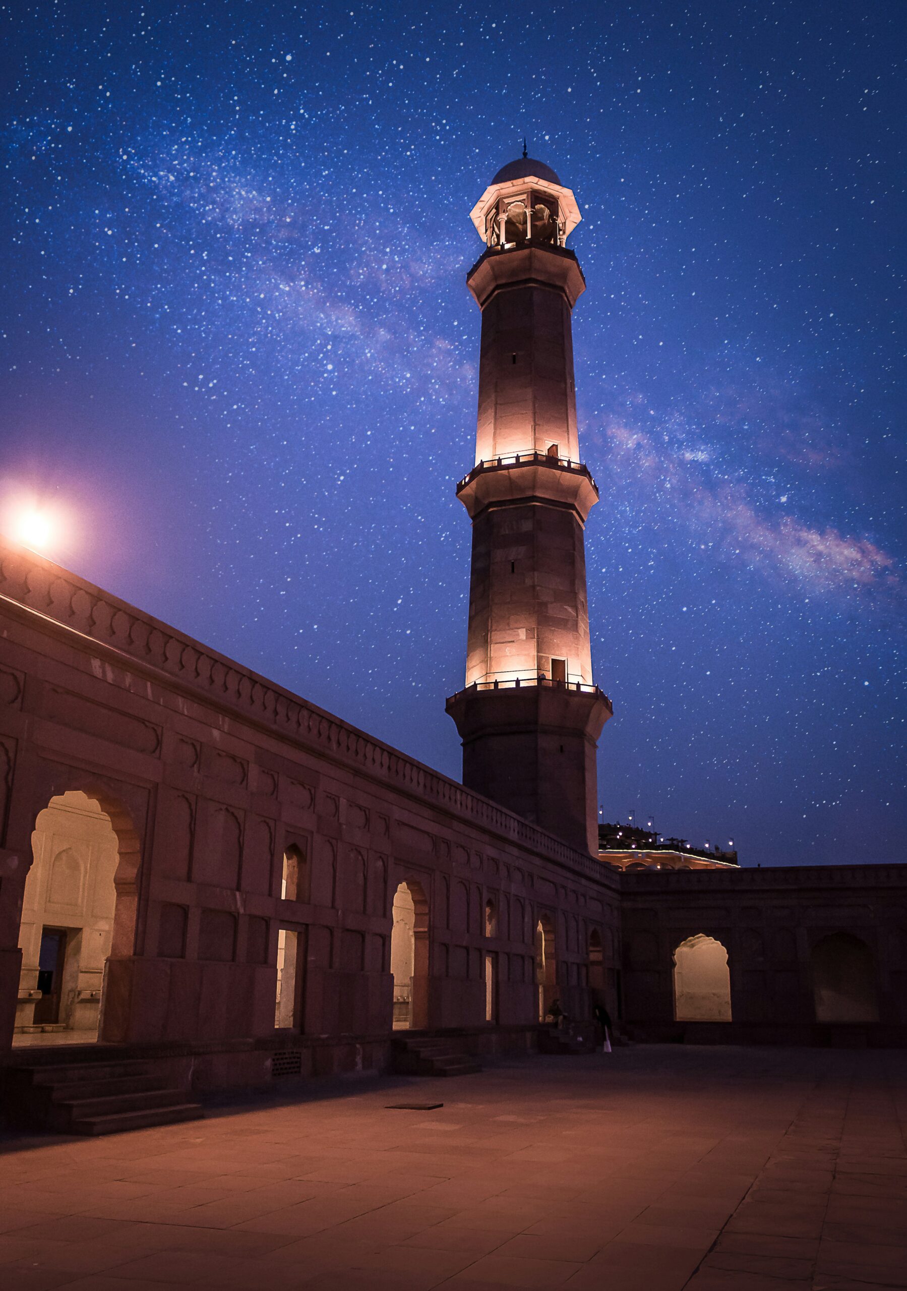 A photo of a prayer mosque with a tower against a night blue sky with stars.